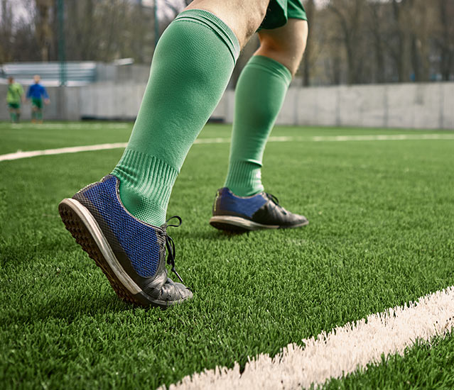 Pies de un futbolista en el césped